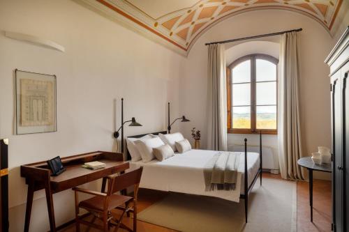 a bedroom with a bed and a desk and a window at Precise Tale Poggio Alla Sala in Montepulciano