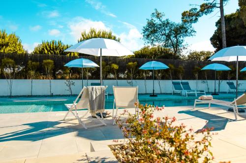 una piscina con 2 sillas y 2 sombrillas en À Espera - Turismo Rural,Melides en Melides