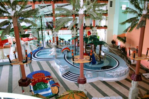 an indoor water park in a mall with palm trees at Laguna Hotel in Magnitogorsk