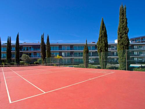 a tennis court in front of a building with trees at Apartment Sunna Residence by Interhome in Vilamoura
