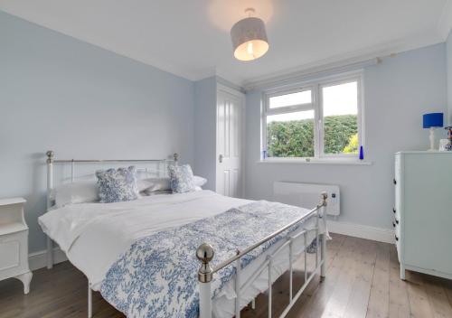 a white bedroom with a bed and a window at Stonehurst in Aldringham