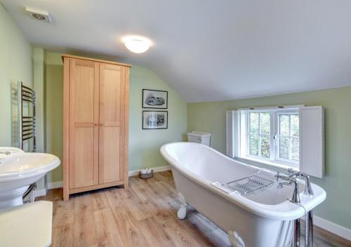 a bathroom with a white tub and a sink at Boot Cottage in Sudbourne