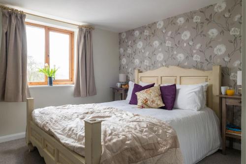1 dormitorio con 1 cama grande con almohadas moradas en Cuckoo Cottage - Luxury Cottages, en Ilfracombe