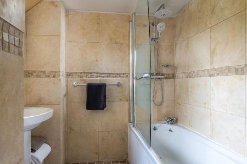 y baño con ducha, bañera y lavamanos. en Cuckoo Cottage - Luxury Cottages, en Ilfracombe