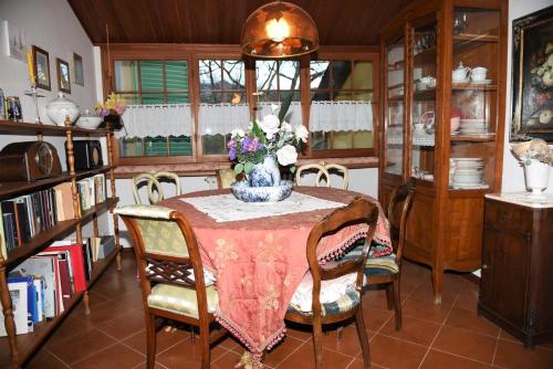 una mesa de comedor con un jarrón de flores. en Casa gialla nel bosco, en Reggello