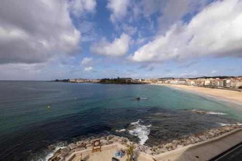 a view of a beach with buildings and the ocean at Apartamentos Rotilio in Sanxenxo
