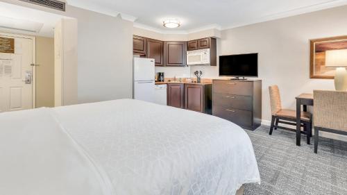 a bedroom with a white bed and a kitchen at Staybridge Suites Savannah Historic District by IHG in Savannah
