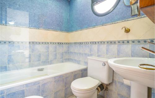 Baño de azulejos azules con aseo y lavamanos en Gorgeous Apartment In Torremolinos With Kitchen, en Torremolinos
