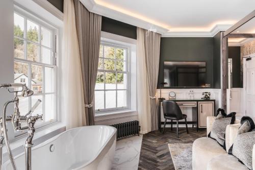 a bathroom with a tub and a living room at Dunkeld House Hotel in Dunkeld