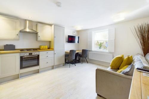 a kitchen and living room with a couch and a table at The Snug Central Cosy Good Wi-Fi in Cheltenham