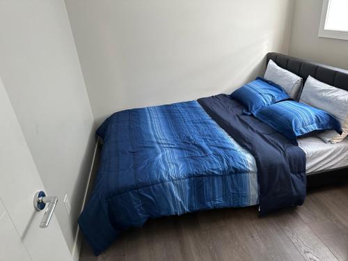 1 cama con sábanas y almohadas azules en una habitación en Cozy BSMT Apt w/2BR+Disney+ Nflx, en Saskatoon