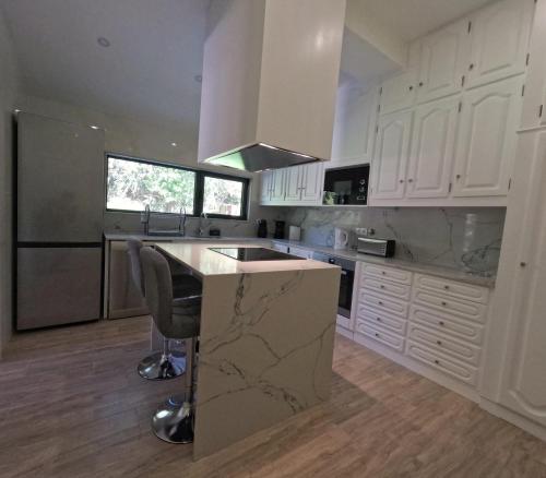 a kitchen with white cabinets and a marble counter top at Casa de Pinheiral in Baião