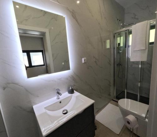 a white bathroom with a sink and a mirror at Casa de Pinheiral in Baião