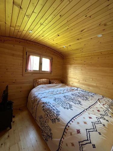 une chambre avec un lit dans une cabane en bois dans l'établissement La p'tite Bohème, à Gouttières