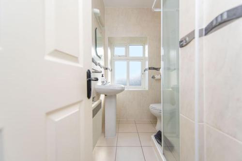 Baño blanco con lavabo y aseo en Clonbur House - Two bedroom village apartment, en Galway