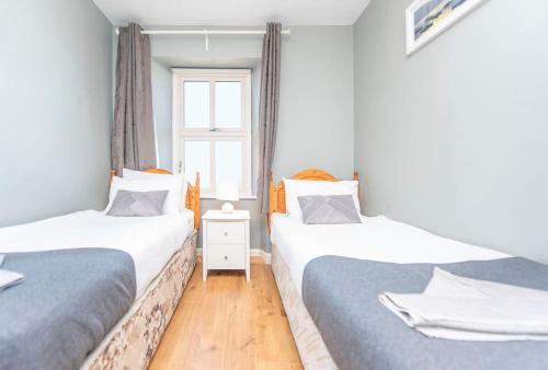 two twin beds in a room with a window at Clonbur House - Two bedroom village apartment in Galway