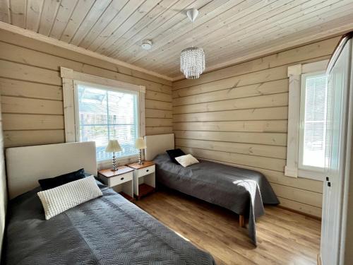 - 2 lits dans une chambre dotée de murs en bois et de fenêtres dans l'établissement Villa Aleksandra, LaatuLomat, à Juva