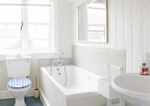 a bathroom with a tub and a toilet and a sink at Suffolk Cottage in Southwold