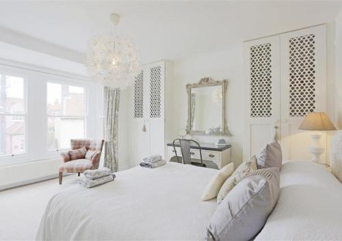 a white bedroom with a large bed and a mirror at Suffolk Cottage in Southwold