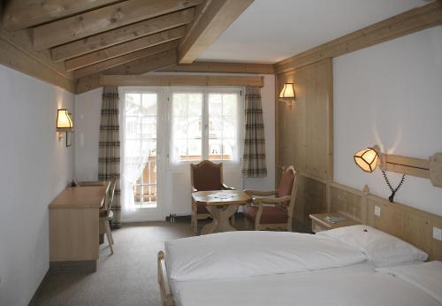 a bedroom with a bed and a desk and a table at Hotel Alte Post in Grindelwald