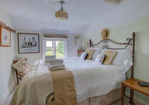 um quarto com uma cama grande e lençóis brancos em Sunset Cottage em Barking