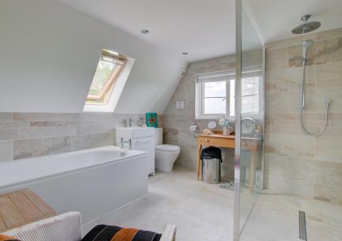 a bathroom with a tub and a toilet and a sink at Sunset Cottage in Barking