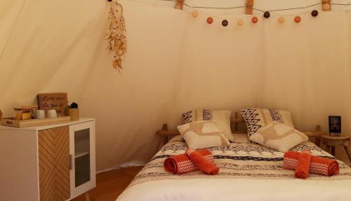 Un dormitorio con una cama con almohadas. en Le tipi à Marie, déconnectez- vous !!!, en Cambounès