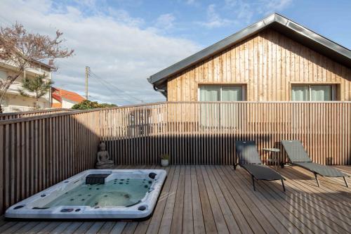 a hot tub on a deck with two chairs and a fence at Ted Surf House in Capbreton