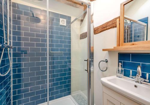 a bathroom with a blue tiled shower and a sink at The Coach House at Hill House in Eye