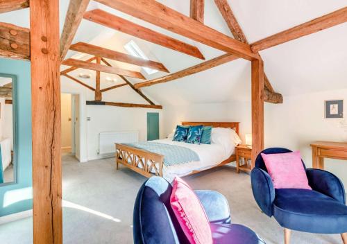 a bedroom with a bed and two blue chairs at The Coach House at Hill House in Eye