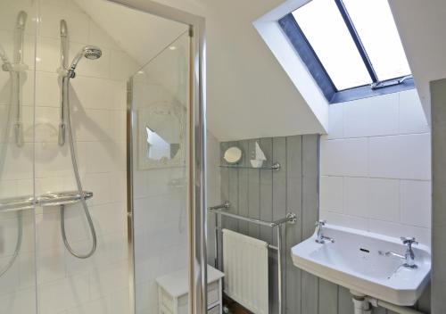 ein Bad mit einer Dusche und einem Waschbecken in der Unterkunft The Coach House in Dunwich