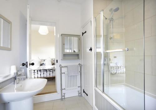 uma casa de banho branca com um lavatório e um chuveiro em The Cornerstone em Southwold