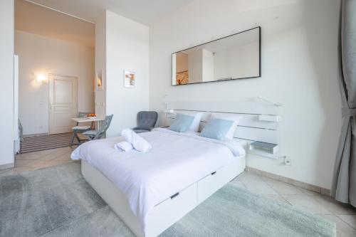 - une chambre blanche avec un grand lit blanc et un miroir dans l'établissement Anastasia, nice studio sea front, terrace, ground floor, à Menton