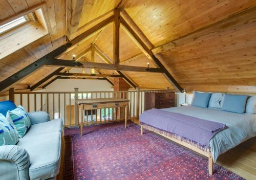 a bedroom with a bed and a couch in a attic at The Folly Barn in Debenham