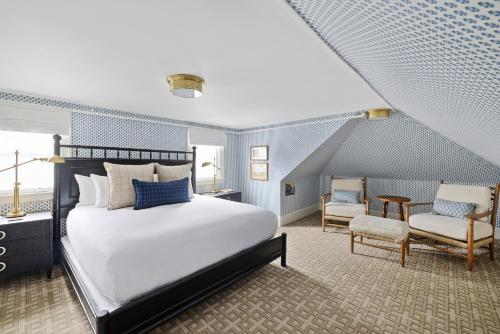 a bedroom with a large white bed and chairs at Kennebunkport Inn in Kennebunkport