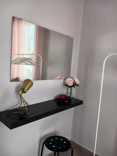 a shelf with flowers and a lamp and a mirror at Angie's Home in Lixouri