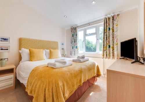 a bedroom with a bed with a yellow blanket and a tv at The Harrier in Aldeburgh