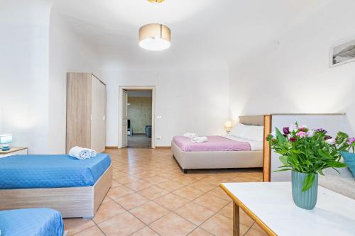 a room with two beds and a table with a vase of flowers at Piazza Pretoria & Quattro Canti Roomy Flats with Balconies in Palermo