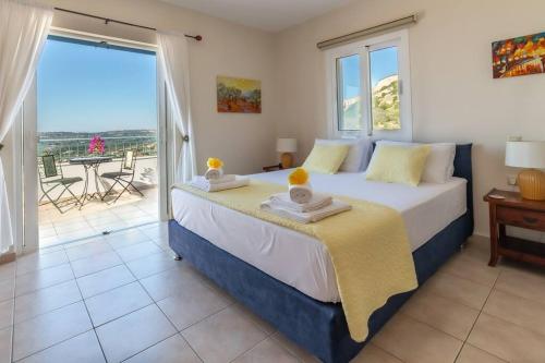a bedroom with a large bed and a balcony at Villa Anna Margarita, beautiful modern villa with far reaching sea views in Kefallonia