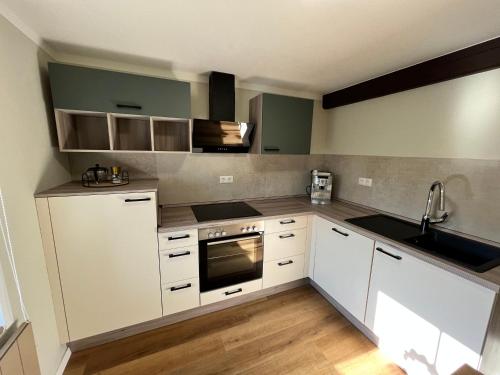 a kitchen with white cabinets and a sink at Suite SZ-Lichtenberg in Salzgitter