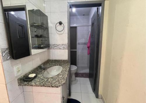 a bathroom with a sink and a toilet and a mirror at Ervino Praia Flat in São Francisco do Sul