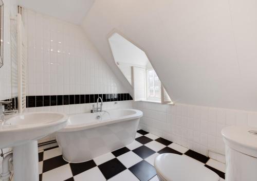 y baño con 2 lavabos, bañera y aseo. en The Pump House, en Orford