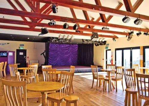 una habitación con mesas y sillas de madera y un escenario en Beacon Fell View, en Longridge