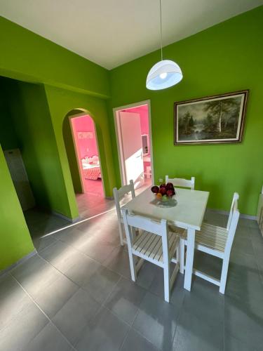 a dining room with green walls and a white table and chairs at Telis Apartments One in Roda