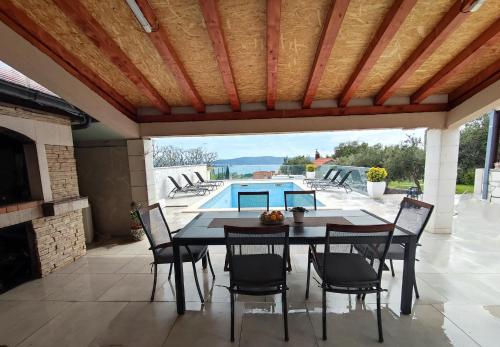 un patio con mesa, sillas y piscina en Holiday house Doris with pool, garden and view, en Kaštela
