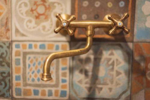a brass faucet attached to a tiled wall at Agriturismo Maso Giomo in Brentonico