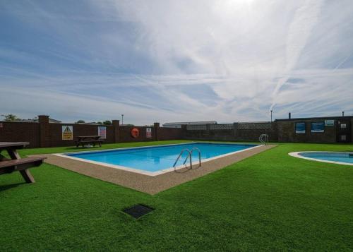 einen Pool in einem Garten mit einer Bank und Gras in der Unterkunft Cockerham Sands in Cockerham