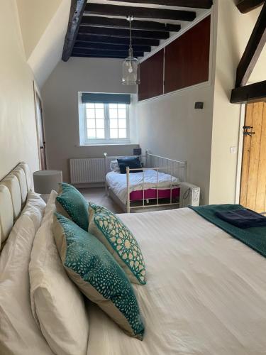 a bedroom with a large bed with pillows on it at The Groom's Cottage in Towcester