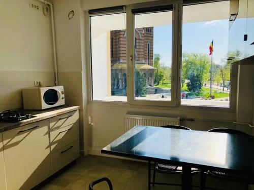 een keuken met een tafel, een magnetron en een raam bij Joy City Stay Victoriei 7G-9 in Timişoara