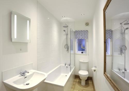 a white bathroom with a sink and a toilet at Tynewold in Southwold